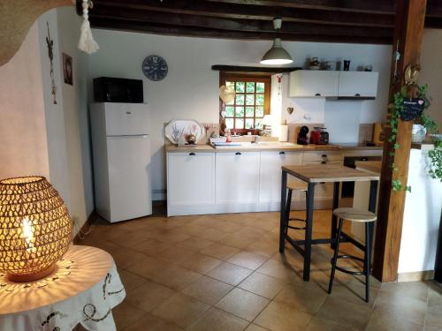 une cuisine avec des armoires blanches et une table dans l'établissement Gîte au calme avec verger, à proximité de randonnées et sites culturels - FR-1-586-9, à Le Châtelet