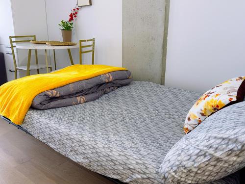 uma cama com um cobertor amarelo e uma mesa em Peace & Elegance in downtown MTL em Montreal