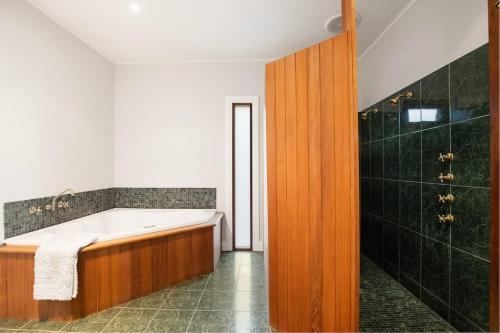 a bathroom with a bath tub and a shower at Strong Farmers Cottage Willunga in Willunga