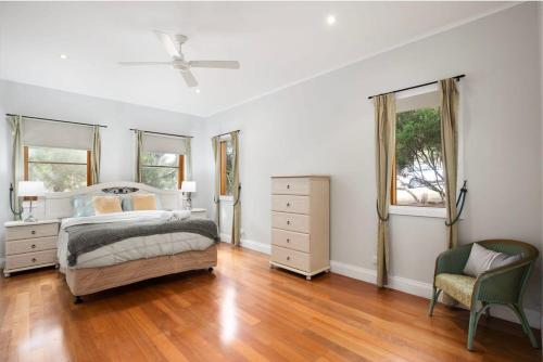 a bedroom with a bed and a dresser and a chair at Strong Farmers Cottage Willunga in Willunga