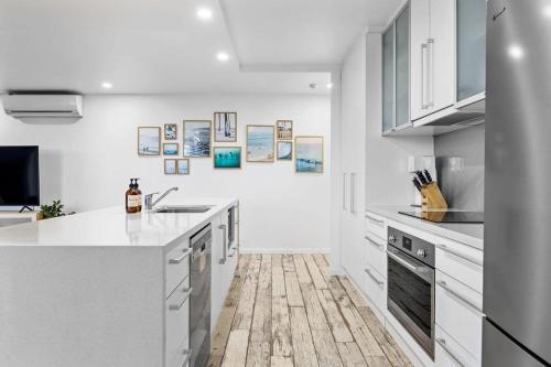 a kitchen with white cabinets and a wooden floor at The Rocks Resort Unit GA in Gold Coast