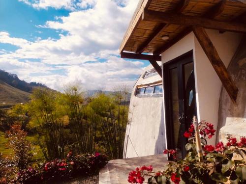 una casa con una puerta y flores delante de ella en Alta vista glamping, en Aranzazu