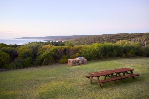 a picnic table in a field with the ocean in the background at Chandlers Smiths Beach Villas in Yallingup