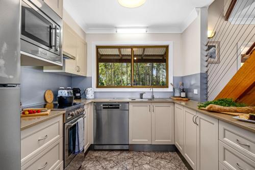 a large kitchen with white cabinets and a window at Ellendale in Kurmond