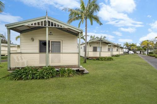 a row of houses on a lawn with palm trees at Teralba Lakeside Caravan Park in Teralba