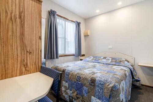 a bedroom with a bed and a chair and a window at Teralba Lakeside Caravan Park in Teralba