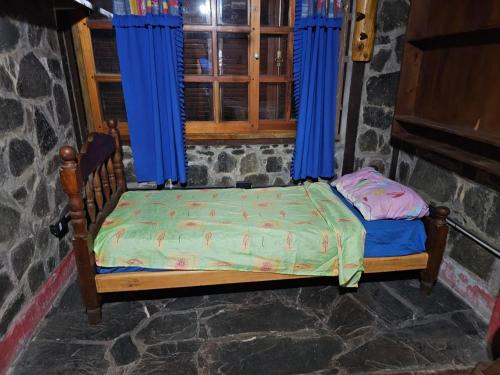 a small bed in a room with blue curtains at alojamiento Villa sarita in Posadas