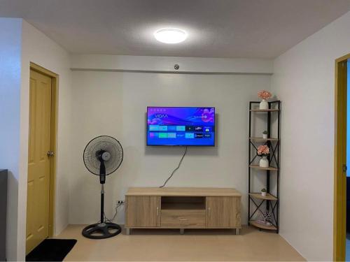 Habitación con ventilador y TV en la pared. en One Spatial Condo en Iloilo