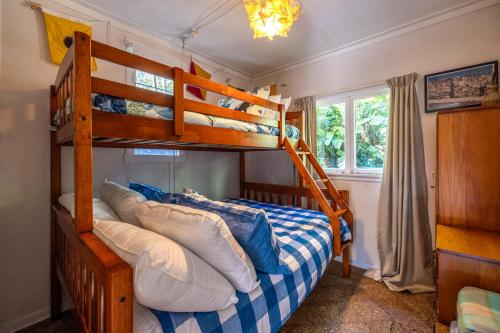 a bedroom with two bunk beds and a bed with pillows at Little Ocean Hideaway in Oneroa