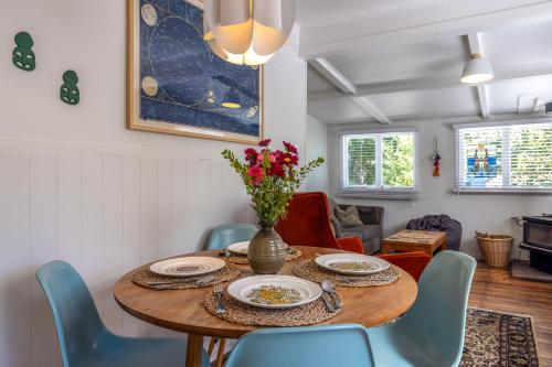 a dining room with a table and blue chairs at Little Ocean Hideaway in Oneroa