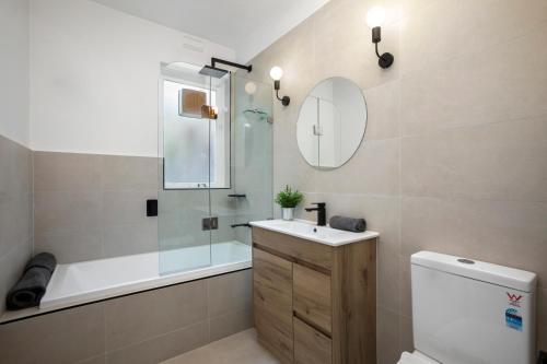 a bathroom with a tub and a sink and a toilet at Complete Host Cromwell Rd Apartments in Melbourne