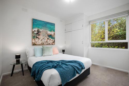 a white bedroom with a bed and a window at Complete Host Cromwell Rd Apartments in Melbourne