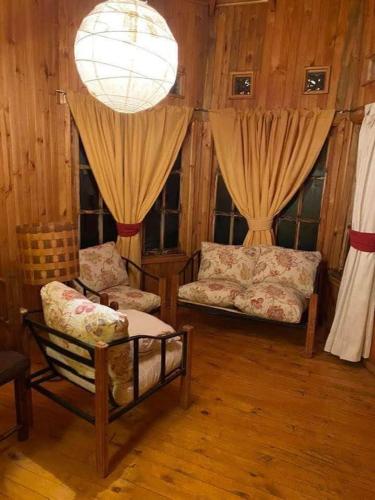 ein Wohnzimmer mit 2 Sofas und einem Kronleuchter in der Unterkunft Refugio Entremontañas in Antuco