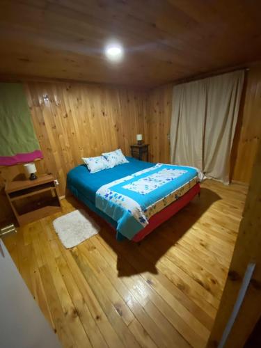 ein Schlafzimmer mit einem Bett in einem Holzzimmer in der Unterkunft Refugio Entremontañas in Antuco