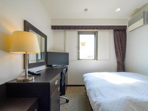 a hotel room with a bed and a desk with a lamp at Center One Hotel Handa in Handa