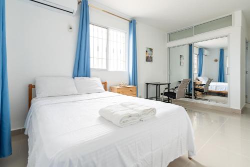 a bedroom with a white bed with towels on it at Casa cerca SDQ & Bus Caribe tours in Santo Domingo