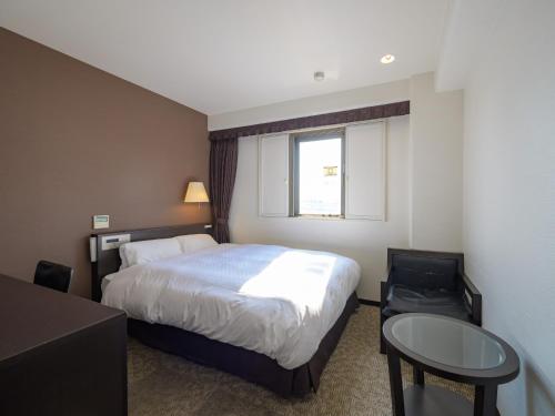 a hotel room with a bed and a table and a window at Centre One Hotel Handa in Handa