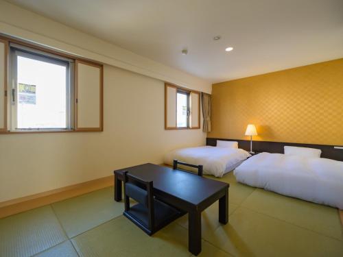 a hotel room with two beds and a table at Centre One Hotel Handa in Handa