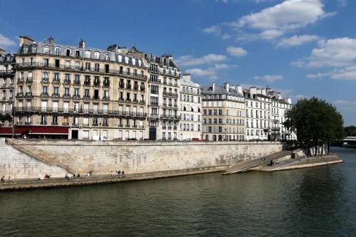 a large building next to a river with buildings at Hôtel Des Deux-Iles - Notre-Dame in Paris