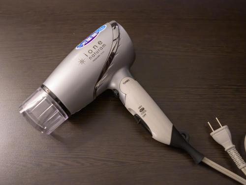 a white electric hair dryer on a wooden table at Centre One Hotel Handa in Handa