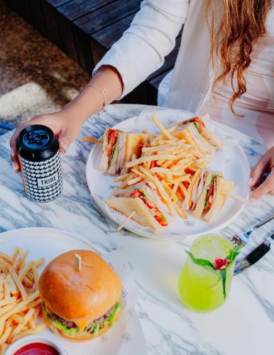 a woman sitting at a table with a sandwich and french fries at Tribe Perth Kings Park in Perth