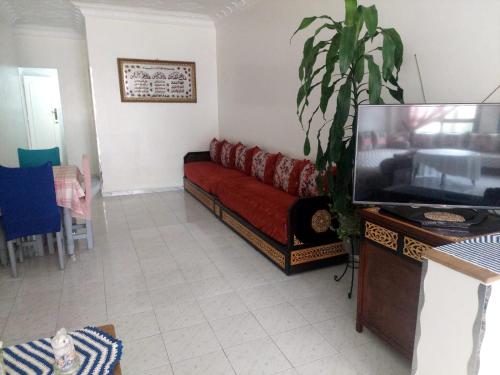 uma sala de estar com um sofá vermelho e uma televisão em Himmich em Asilah