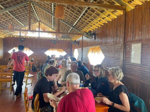 eine Gruppe von Personen, die in einem Restaurant an Tischen sitzen in der Unterkunft Hoàng Su Phì - Móng Ngựa Homestay in Ha Giang