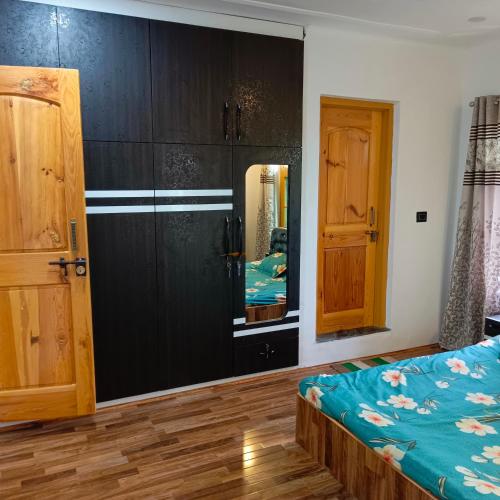 a bedroom with black cabinets and a bed and a mirror at The Himalayan Inn homestay in Gulmarg