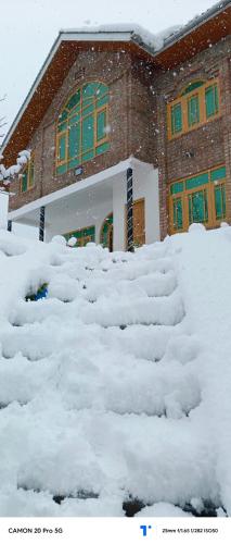 a snow covered yard in front of a building at The Himalayan Inn homestay in Gulmarg