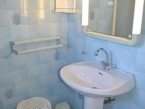 La salle de bains est pourvue de carrelage bleu, d'un lavabo et d'un miroir. dans l'établissement Maison avec grand jardin à 40m de la plage, prox. centre-ville, 3 ch, terrasse plein sud - FR-1-22-255, à La Tranche-sur-Mer