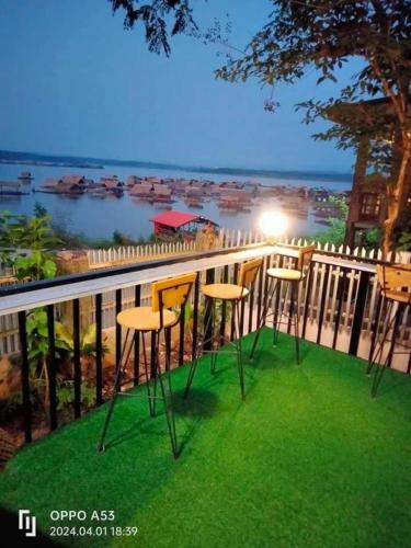 a group of stools on a balcony overlooking the water at บ้านระเบียงน้ำวังใหญ่ in Wang Sam Mo