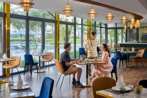 a group of people sitting at a table in a restaurant at Wyndham Hoi An Royal Beachfront Resort & Villas in Hoi An