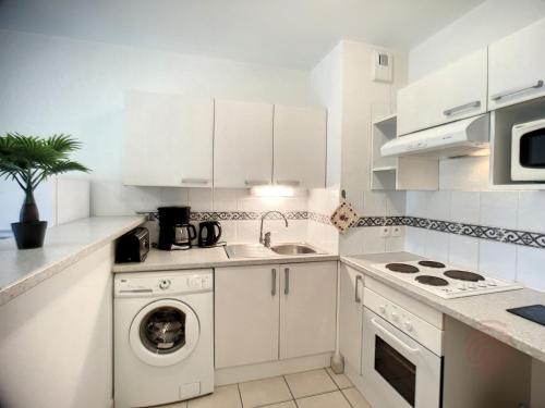 une cuisine avec des armoires blanches et une machine à laver dans l'établissement Appartement F2 climatisé avec terrasse, proche centre-ville et thermes, animaux acceptés - FR-1-451-117, à Lamalou-les-Bains
