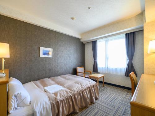 a hotel room with a bed and a window at Hotel Green Park Suzuka in Suzuka