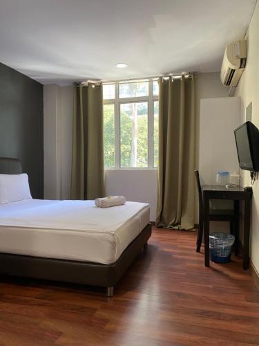 um quarto com uma cama, uma secretária e uma televisão em 1st inn hotel subang em Subang Jaya
