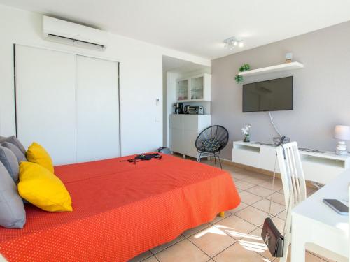 - une chambre avec un lit rouge et une télévision dans l'établissement Studio climatisé 2 pers proche plage et commerces avec balcon et wifi à Saint-Raphaël - FR-1-466A-28, à Saint-Raphaël