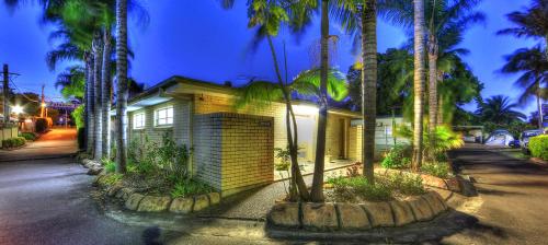 a house with palm trees in front of a street at Paradise Palms Caravan Park in Rathmines