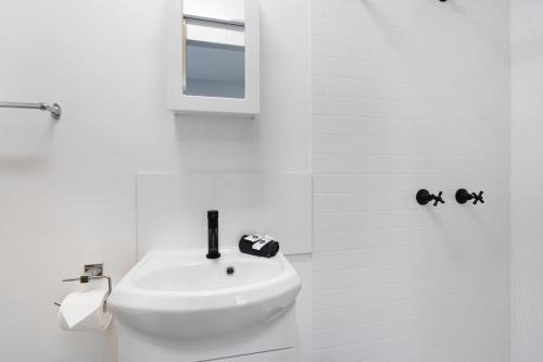 een witte badkamer met een wastafel en een spiegel bij Paradise Palms Caravan Park in Rathmines
