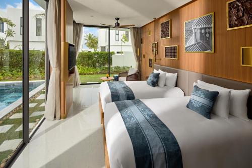 two beds in a hotel room with a pool at Wyndham Hoi An Royal Beachfront Resort & Villas in Hoi An