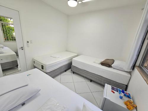 a white room with two beds and a mirror at Quarto Privativo em Condominio in Rio de Janeiro