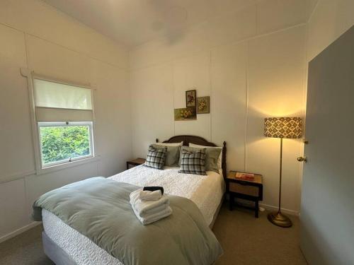 a bedroom with a bed and a lamp and a window at Clementine Cottage in Crows Nest