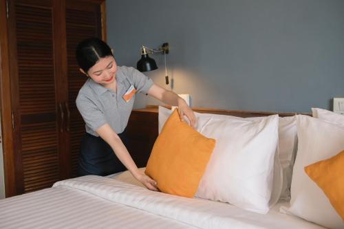 a woman putting a pillow on a bed at Pakse hotel & Restaurant in Pakse