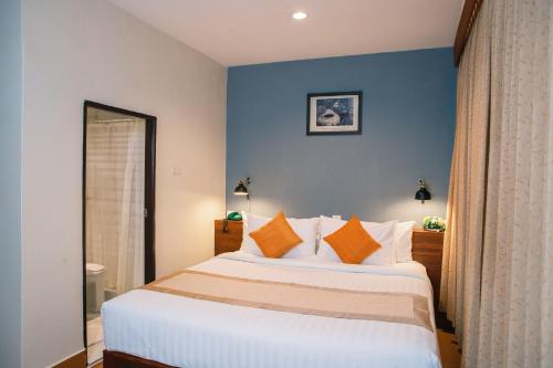 a bedroom with a large white bed with orange pillows at Pakse hotel & Restaurant in Pakse