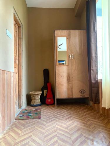 a room with a door with a guitar next to it at Apple Blush Retreat - Tirthan Valley in Gushaini