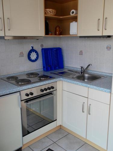 a kitchen with white cabinets and a stove and a sink at Ferienhof Manowski Nr2 in Hinrichsdorf