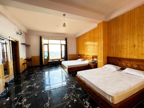 two beds in a room with wooden walls at Hawk Eye Resort in Shimla