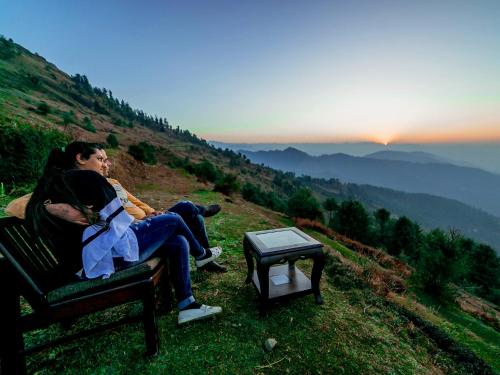 two people sitting on a bench watching the sunset at Hawk Eye Resort in Shimla