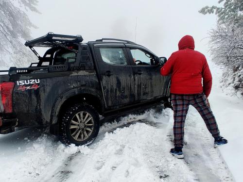 a person standing next to a black truck in the snow at Hawk Eye Resort in Shimla