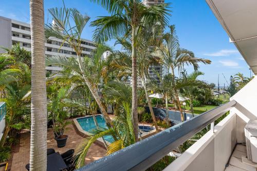 a balcony with palm trees and a swimming pool at Hi Ho Beach Apartments on Broadbeach in Gold Coast