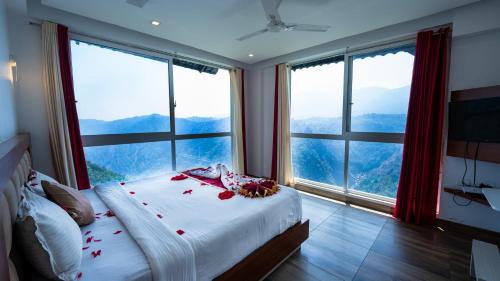 Hilton Cloud Resort في واياناد: غرفة نوم بنوافذ كبيرة وسرير عليه ورد